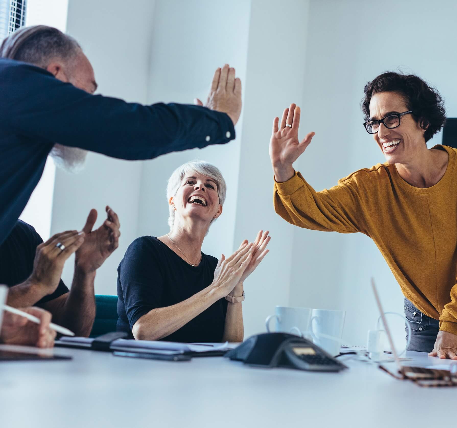 A team of career behavioral health counselors and therapist high five after a team meeting