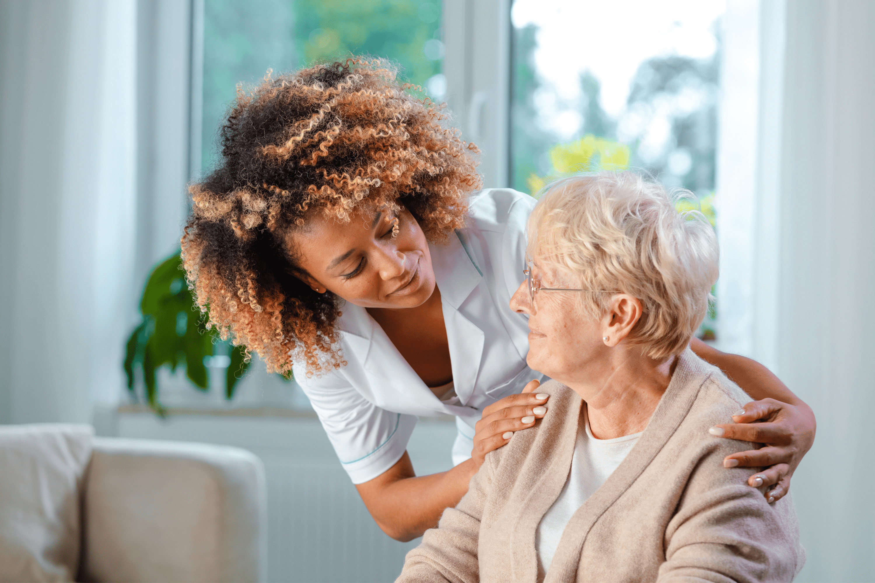 A caregiver smiles over the shoulder of an older woman with IDD