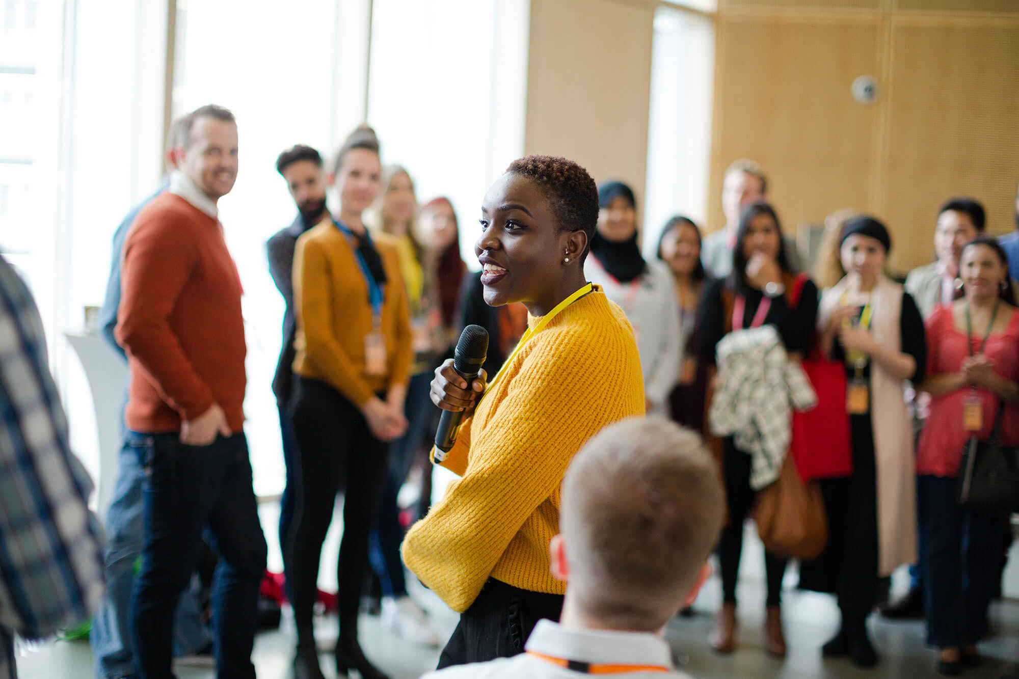 Woman holding a microphone, smiling at a community presentation event