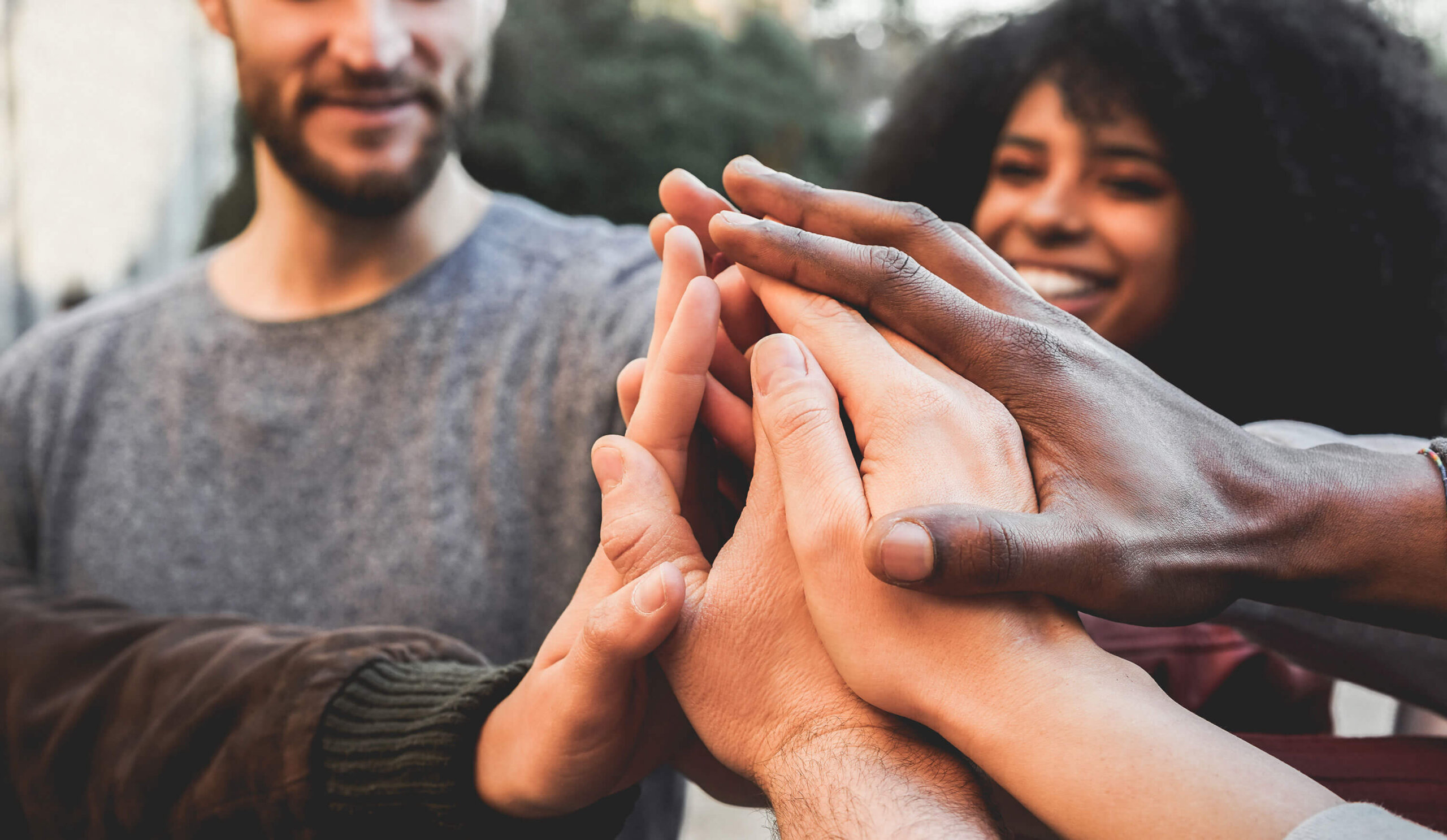 Diverse group of people joining hands in the center of the group