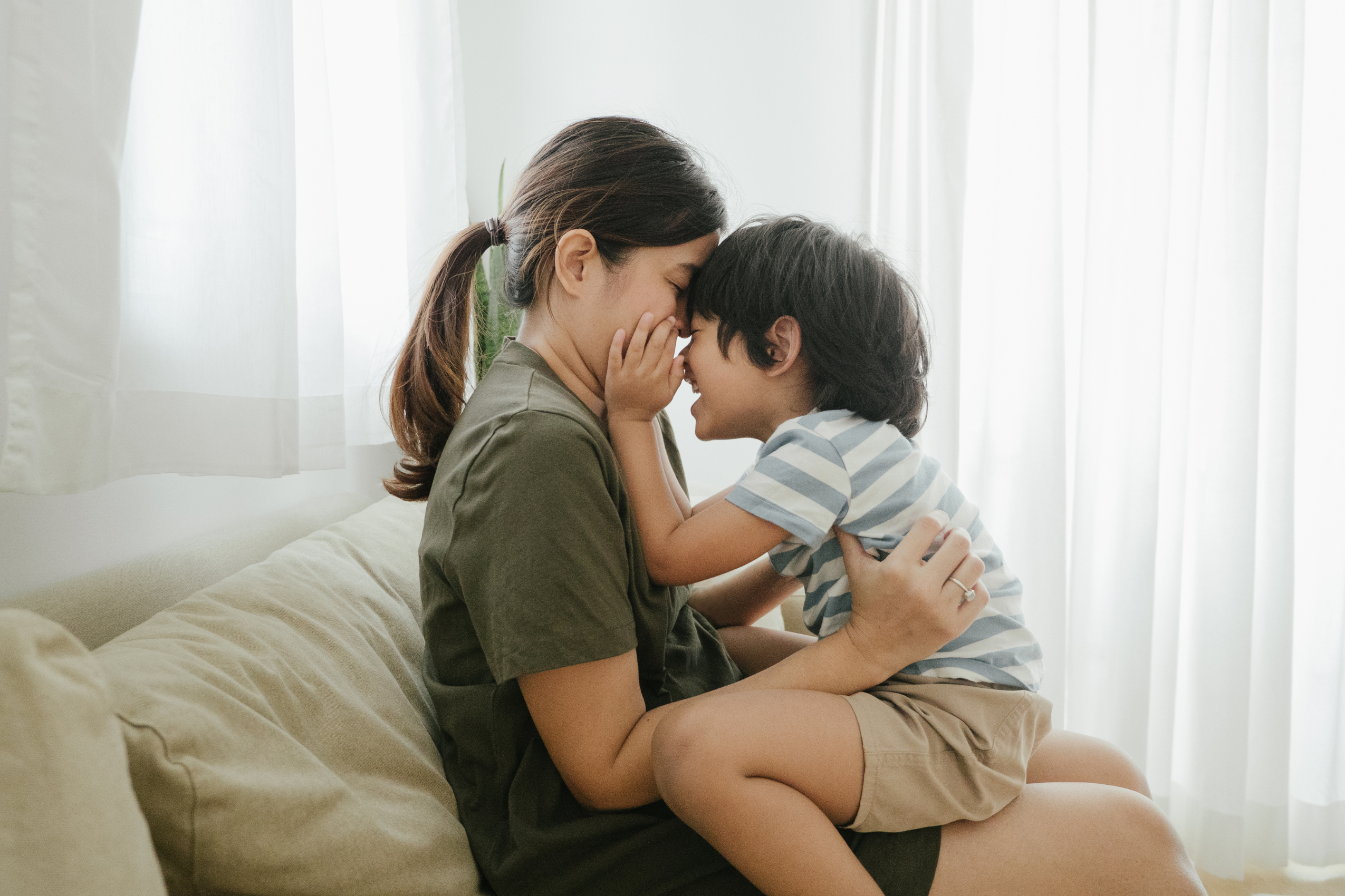 Boy and mother smile forehead to forehead